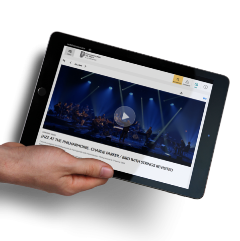 Main tenant une tablette affichant la page d'accueil de la Philharmonie de Paris à la demande